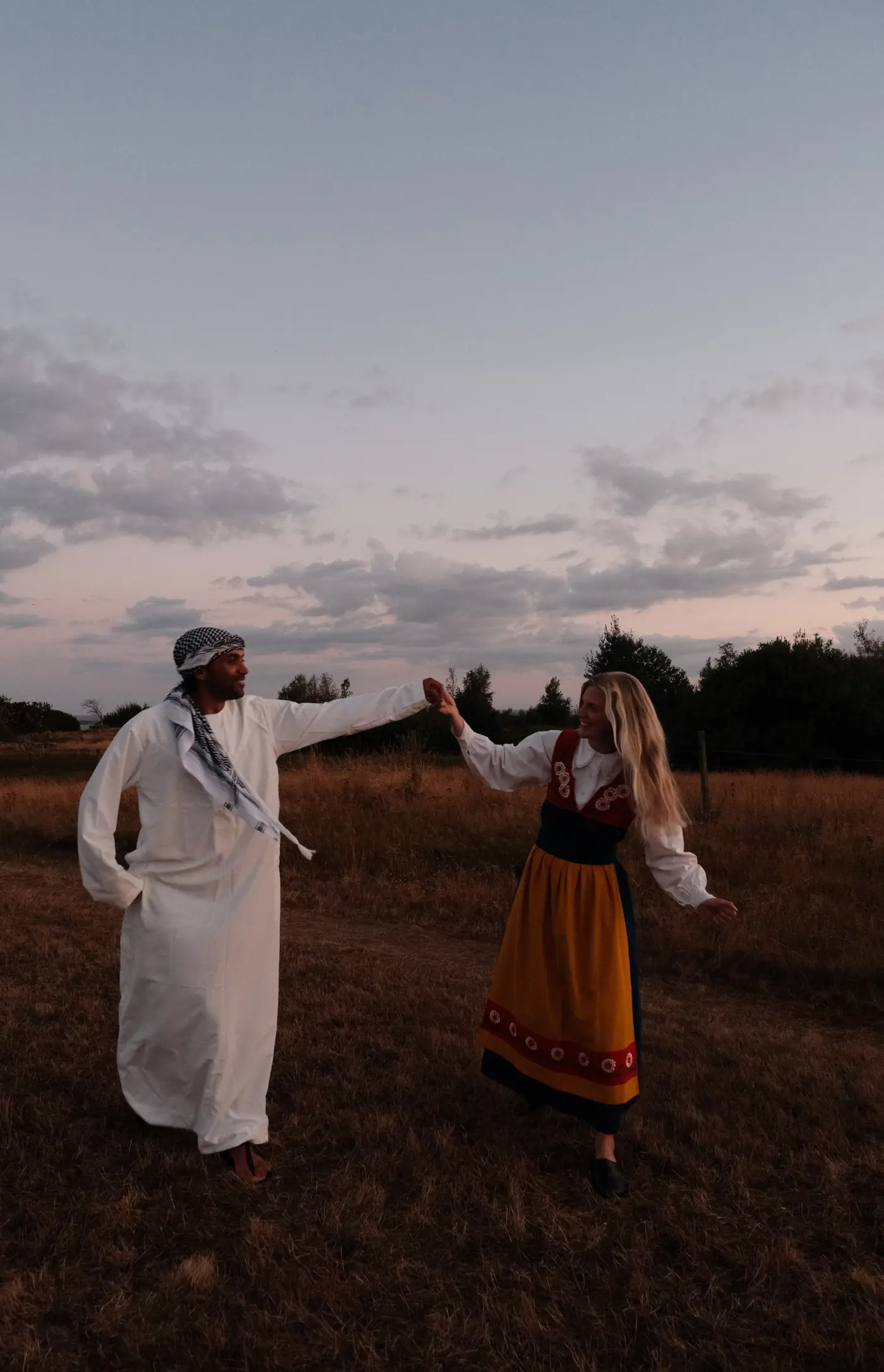 Alice och Yazan dansar hand i hand i ett torrt fält i skymningen. Han i vit thobe och kufiya, hon i Varbergsdräkt.